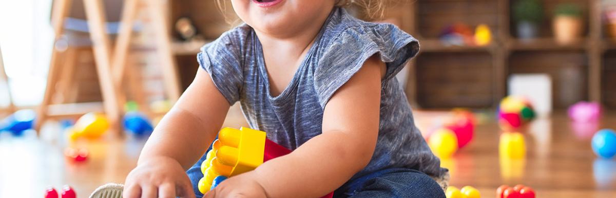 Toddler girl sitting on the floor playing with building blocks toys