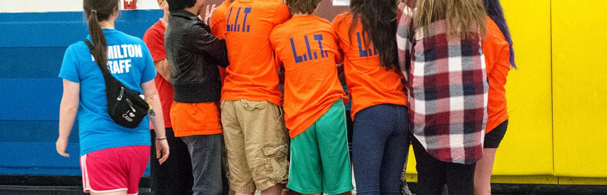 Group of youth huddled on the court with Leadership in Training tshirts