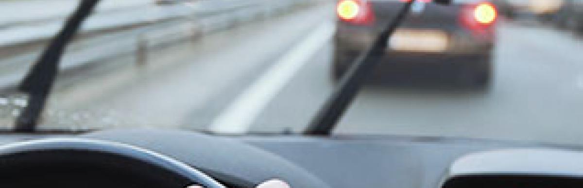 Man driving car with wipers on wet road