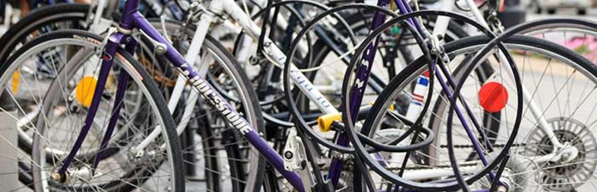 Numerous bikes parked and chained to bike rack on street