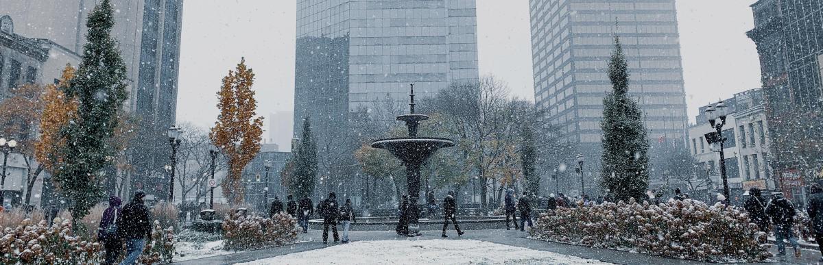 People walking by Gore Park fountain with snow lightly falling
