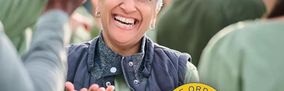 Woman with a clipboard addressing people outside in team activity