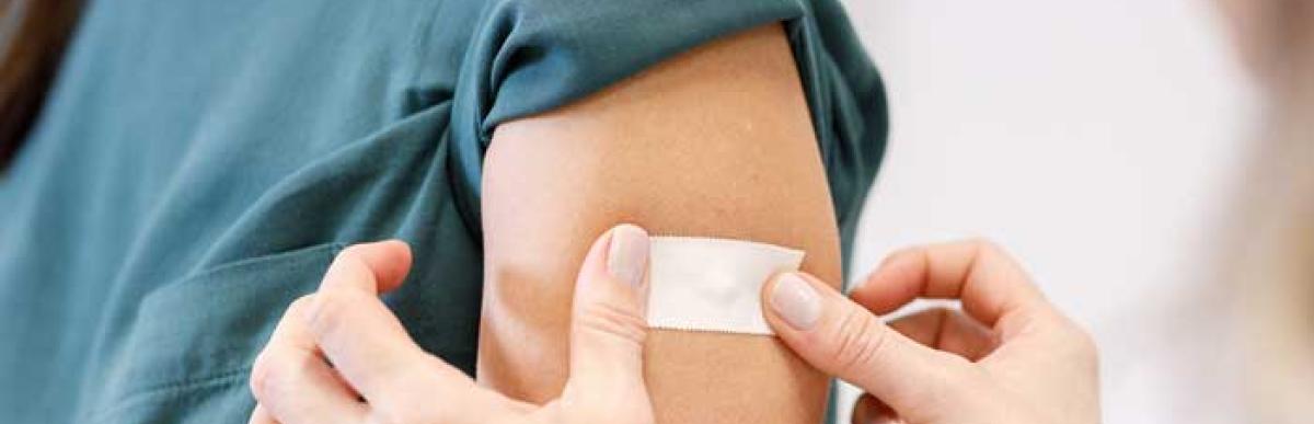 Person getting a bandaid put on their arm after a vaccine