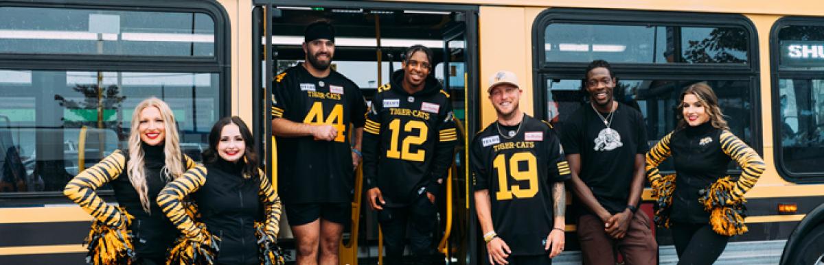 Ticats and cheerleaders in front of bus