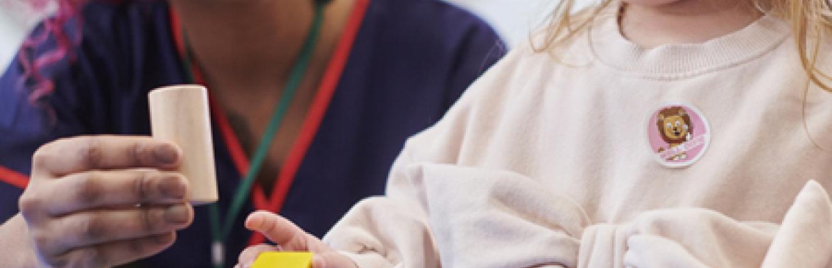 Woman and child playing with colourful wooden blocks at a table