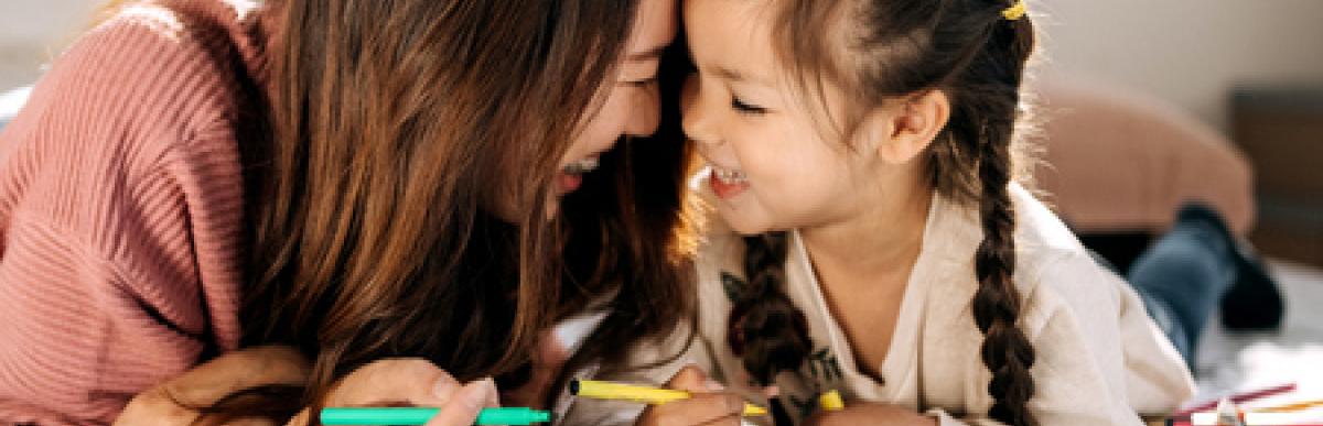 Woman and child lying on floor with markers and colouring book