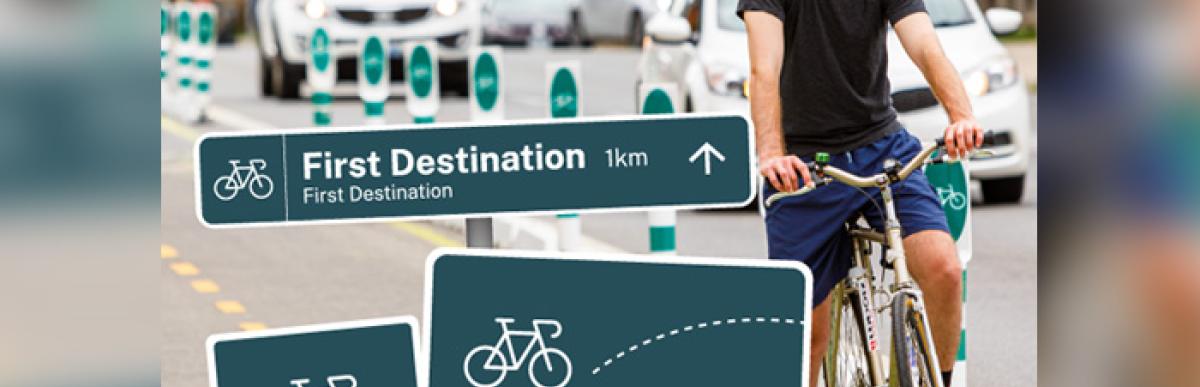 man on a bicycle in the background with wayfinding signs in the foreground