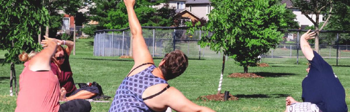 Two women and a City of Hamilton Recreation leader doing Yoga outdoors in a park