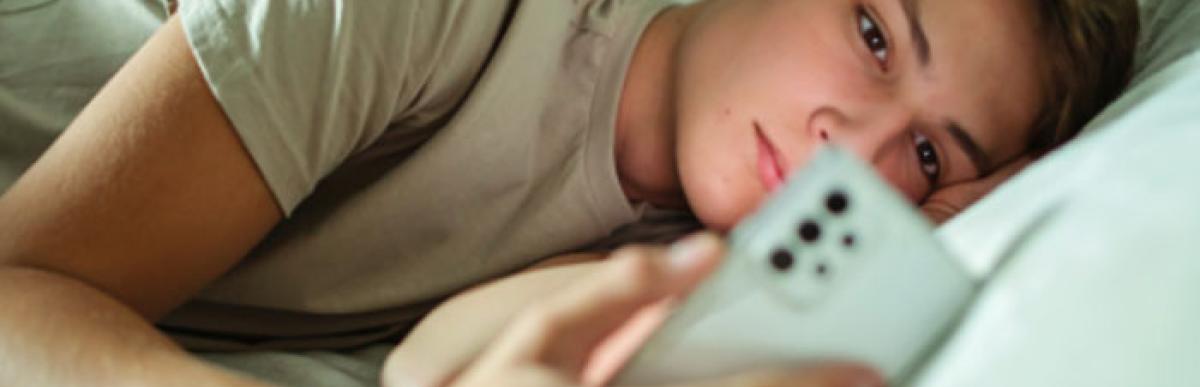 Teenager lying in bed staring at smart phone