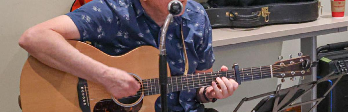 Grey-haired man playing the guitar