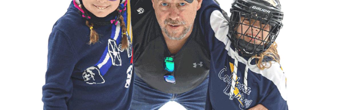 Man and two children preparing to skate on an indoor ice rink