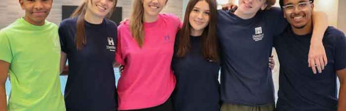 Six smiling teenagers inside of a recreation centre gymnasium
