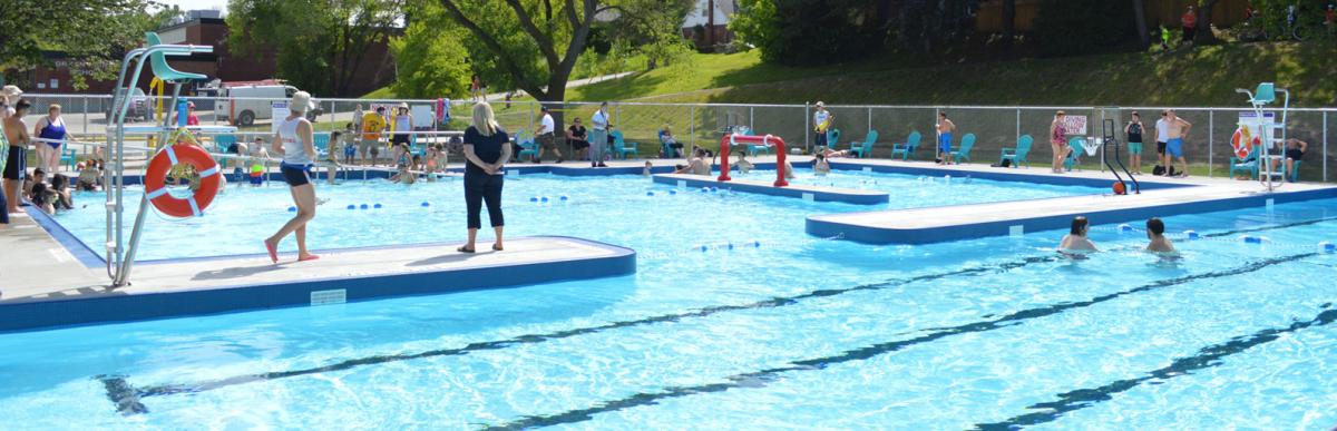 Outdoor City of Hamilton pool in summer with people swimming and recreation staff supervising