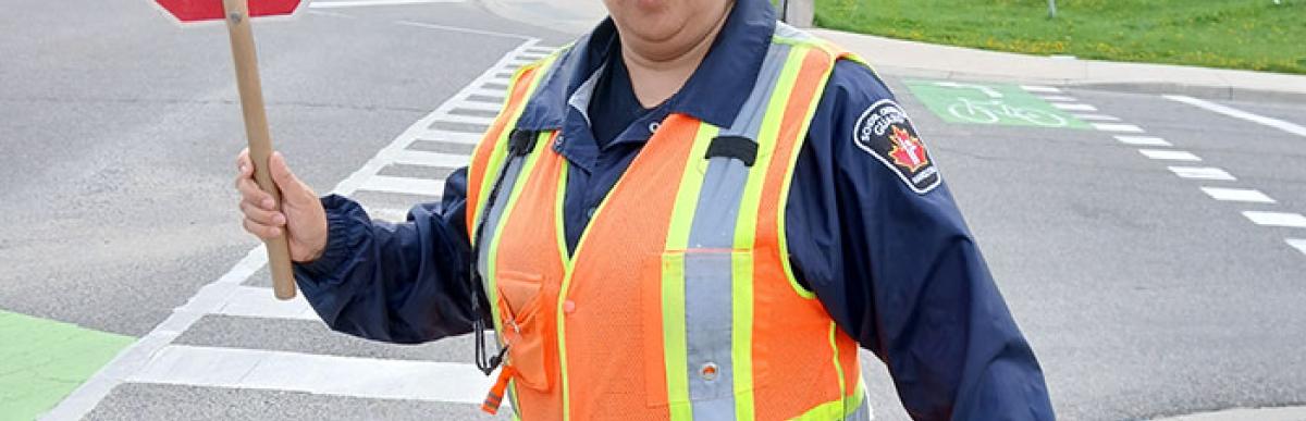 School crossing guard holding up stop sign at crosswalk