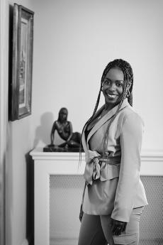 black and white photo of woman in front of sculpture on a table