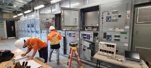 Interior of Electrical Power Centre, two workers in hard hats working at a table