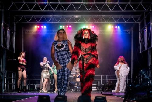 Drag performers in colourful costumes walking on stage at Pride at the Pier.